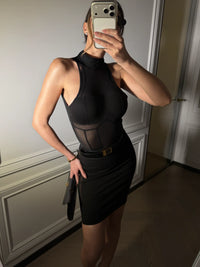 Person wearing a black dress with mesh panels in a room. #color_black