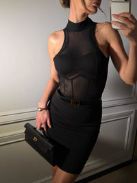 Woman in a black outfit holding a briefcase, taking a mirror selfie. #color_black