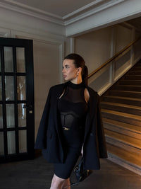 Woman in a black outfit standing in a room with a staircase #color_black