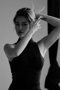 Black and white photo of a woman posing with one arm raised. #color_black